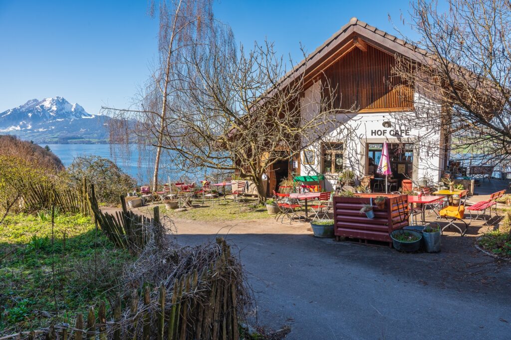 Gebäude des Haldihofs (Hofcafé) mit dem See und den Bergen im Hintergrund
